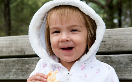 A young girl having a tea-break on a bench in a public parkの写真素材