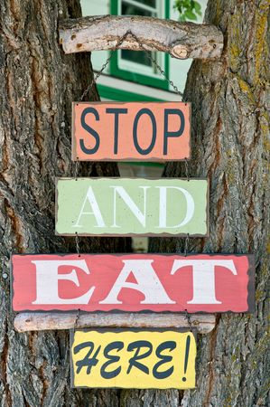 "Stop and eat here" sign on tree trunkの写真素材