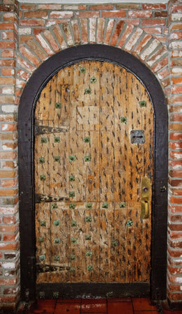 Rustic wooden door with metal decoration on brick wallの写真素材