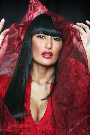 Beautiful east girl in a red dress lifts over the face a veilの写真素材