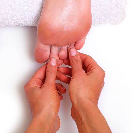 Massage and leaving of the female feet bared by a foot, isolated on a white background, please see some of my other parts of a body imagesの写真素材