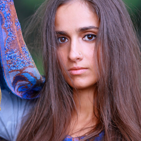 Portrait of the young beautiful girl against trees with green foliageの写真素材