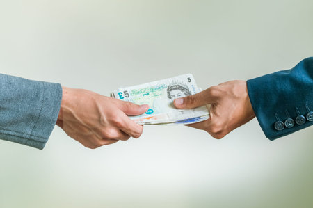 Two businessmen exchanging british money pounds sterling on white background