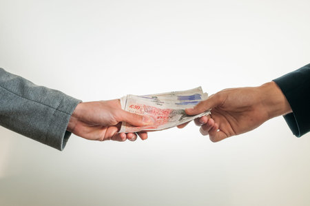 Two businessmen exchanging british money pounds sterling on white background