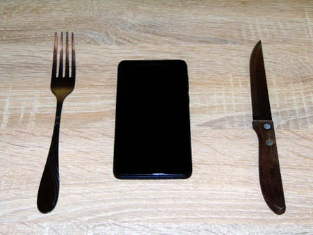 smartphone, knife and fork on tableの写真素材