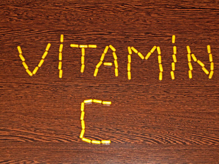 vitamin c text written from organic vitamin c capsules on wooden background