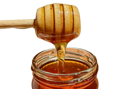 polyflora bee honey flowing into a jar from a wooden spoon. The concept of beekeepingの写真素材