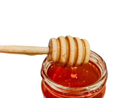 polyflora bee honey flowing into a jar from a wooden spoon. The concept of beekeepingの写真素材