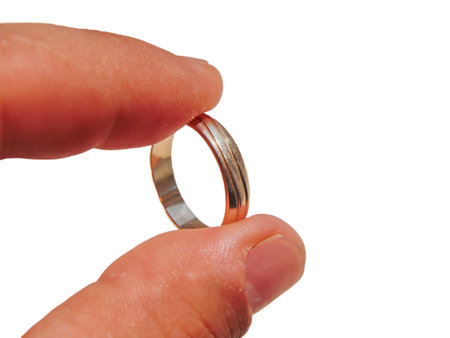 a person holds a gold wedding ring between his fingers