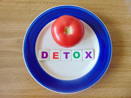 The word detox in colorful letters on a plate with a tomato on it. Detox conceptの写真素材