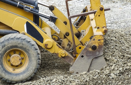 A backhoe loader works with a pile of stone