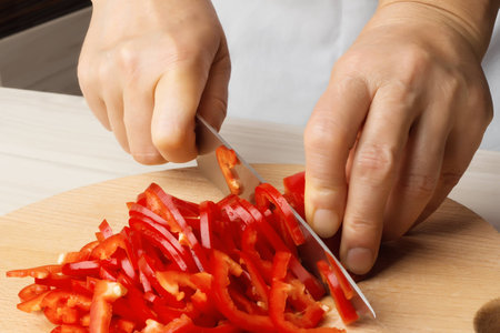 Female hands cutting red peppers の写真素材