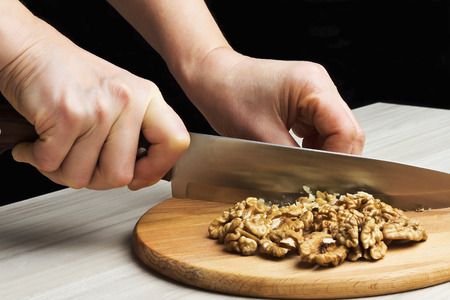 Chopped walnuts with a knife on a wooden cutting boardの写真素材