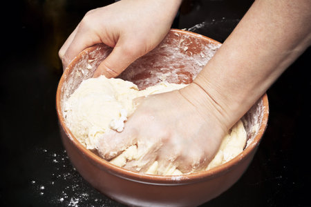 Woman kneading bread dough in kitchen