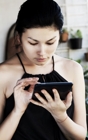 Beautiful young woman reading e-book.の写真素材