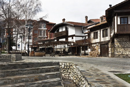 Bansko, Bulgaria - March 20, 2017: Old house stone paved road alley, wooden benches Bansko ski tourist centre of Bulgariaの写真素材