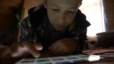 boy lays in a bed and touches on a tablet PC at homeの写真素材