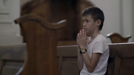 serious boy praying in the Church aloneの写真素材