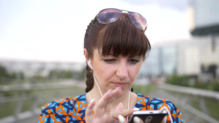 Woman Uses a Smartphone Listening to Musicの写真素材