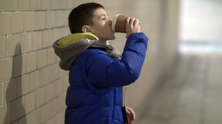 boy drink hot coffee in the tunnel, waiting for someone, delay, winterの写真素材