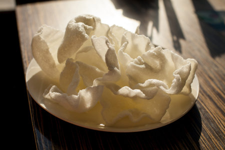 Chips from white rice. Crispy rice cracker on a white plate, on a wooden table. Crispy crackers....