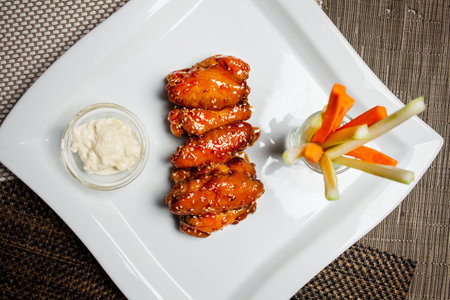Chicken in sweetly sour sauce with sesame seeds, with vegetables in a white square plate on food mat - bamboo mat for food background. Photo for backgroundの写真素材