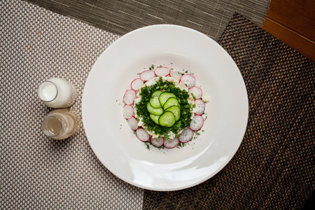 Original - unusual okroshka. Traditional summer light cold yoghurt soup with cucumber, radish, eggs and dill on the food - bamboo mat. Nearby there is soda and kvass in bottles. selective focus.の写真素材
