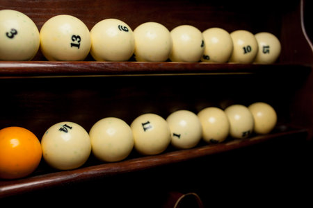 Balls for pool billiards on the shelf, billiard balls for American billiards, balls for Russian billiards, colored or white balls for billiards on a wooden background. Close-up photo. Soft focus.の写真素材