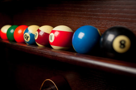 Balls for pool billiards on the shelf, billiard balls for American billiards, balls for Russian billiards, colored or white balls for billiards on a wooden background. Close-up photo. Soft focus.の写真素材