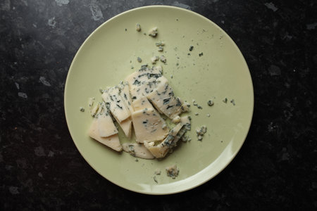 blue cheese with mildew on a light plate on black background. Blue cheese. Cheese with edible mildew on a light plate on black background. Top view.の写真素材