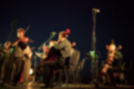Background for design, blur texture, actors on stage scene in concert with silhouettes of people. De focused, Blurred image of the conductor introducing musical composition before performance.の写真素材