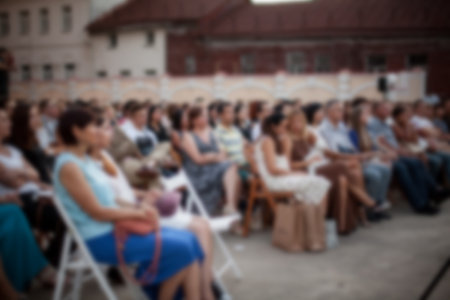 People are watching a concert of classical music. blurred young and adult women and men and other people watching listening to concert of classical band in daylight outdoor enviroment.の写真素材