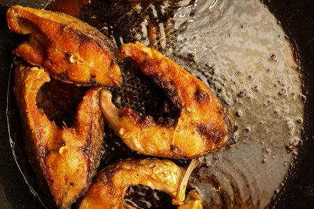 Fried fish snacks on frying pan. pieces of fried fish. pieces of fried fish in boiling oil. pieces of fried fish in hot oil in a frying panの写真素材