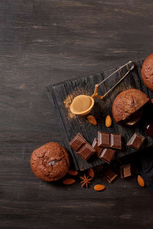 homemade muffins with chocolate, chocolate bars and almonds grains on a black wooden background. Cook prepares muffins with chocolate in the kitchen. Cook prepares muffins with chocolate in the bar.の写真素材