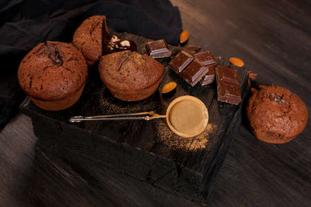 homemade muffins with chocolate, chocolate bars and almonds grains on a black wooden background. Cook prepares muffins with chocolate in the kitchen. Cook prepares muffins with chocolate in the bar.の写真素材