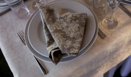 Classic design of the table. Table setting: brown napkin, knife and fork, wine glasses. served for...