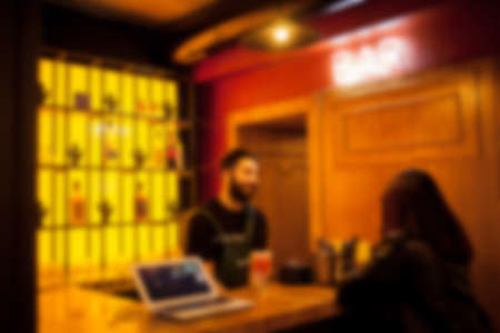 People rest in an ethnic, Mexican restaurant. Blurred photo. blur photo of restaurant with long table dinner and chair along it with bokeh light with yellow tone colorの写真素材