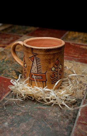 clay brown mug, mugs with a pattern, stand on the tile. clay mug with a pattern. Painted clay mug on black background.の写真素材