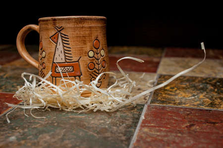 clay brown mug, mugs with a pattern, stand on the tile. clay mug with a pattern. Painted clay mug on black background.の写真素材