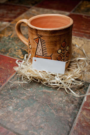 clay brown mug, mugs with a pattern, stand on the tile. clay mug with a pattern. Painted clay mug on black background.の写真素材