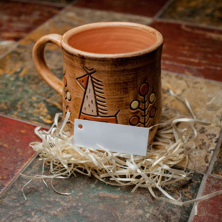 clay brown mug, mugs with a pattern, stand on the tile. clay mug with a pattern. Painted clay mug on black background.の写真素材
