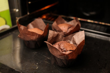 Cake chocolate fondant cake in home oven on the dark black background. Good for menu receipt book design. chocolate muffins on a dark background. chocolate muffins in the oven on the baking sheetの写真素材