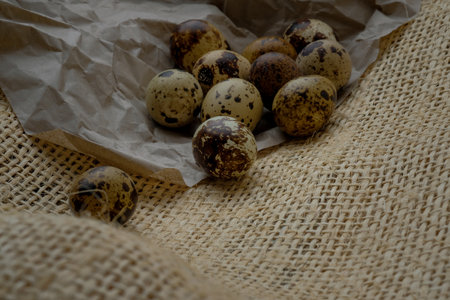 Easter quail eggs on craft paper and rustic burlap background. Easter eggs on craft paper and burlap fabric texture. Spring background with small easter quail eggs.の写真素材