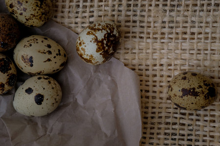 Easter quail eggs on craft paper and rustic burlap background. Easter eggs on craft paper and burlap fabric texture. Spring background with small easter quail eggs.の写真素材