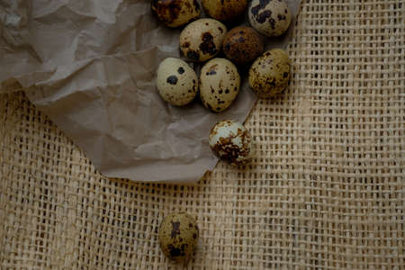 Easter quail eggs on craft paper and rustic burlap background. Easter eggs on craft paper and burlap fabric texture. Spring background with small easter quail eggs.の写真素材