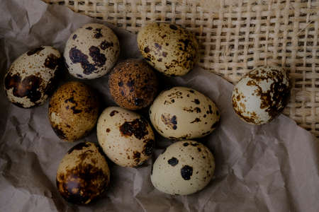 Easter quail eggs on craft paper and rustic burlap background. Easter eggs on craft paper and burlap fabric texture. Spring background with small easter quail eggs.の写真素材