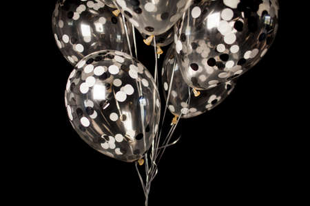 Black and white balloons on a dark black background. Celebration concept, White and black balloons on a dark black background for a holiday, birthday or other holiday. Photo for posters or postcards.の写真素材