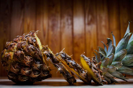 Sliced pineapple on a wooden background. Ripe pineapple on brown wooden background. Pineapple and pineapple pieces on an old wooden background.Close-up photoの写真素材