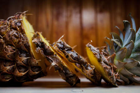 Sliced pineapple on a wooden background. Ripe pineapple on brown wooden background. Pineapple and pineapple pieces on an old wooden background.Close-up photoの写真素材