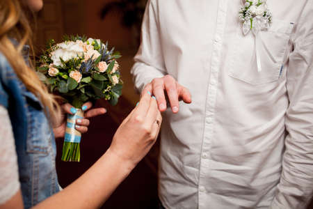 Newlyweds exchange rings, groom puts the ring on the bride's hand in marriage registry office. wedding rings and hands of bride and groom. young wedding couple at ceremony. matrimony.の写真素材